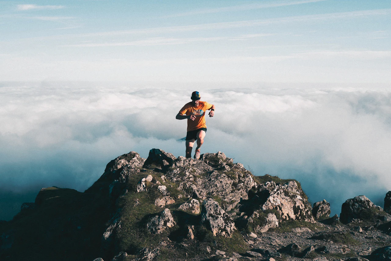 Corredor en una cumbre rocosa por encima de un mar de nubes